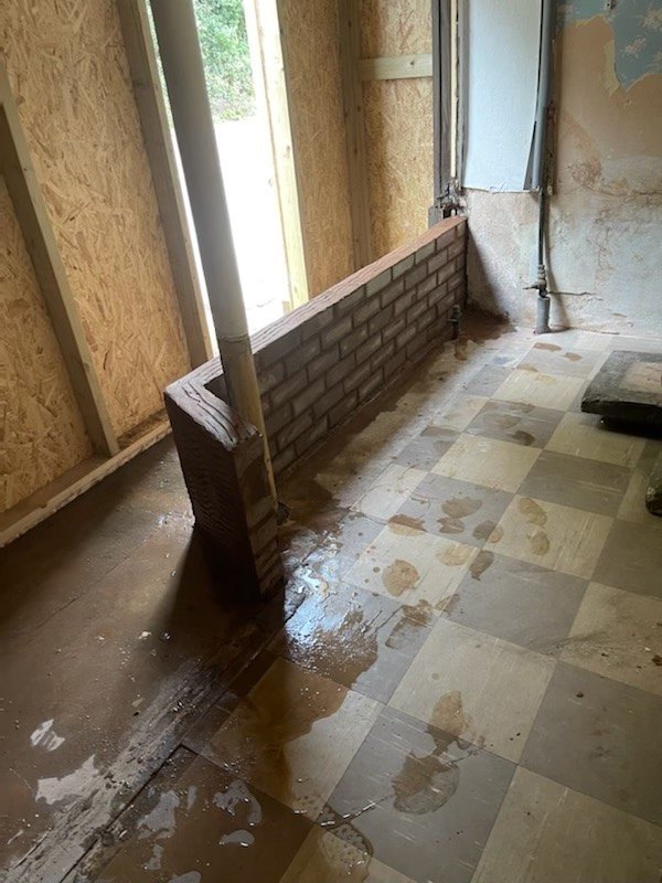 Inside The Old Bakery after the impact, with boarded openings & a wet tiled floor