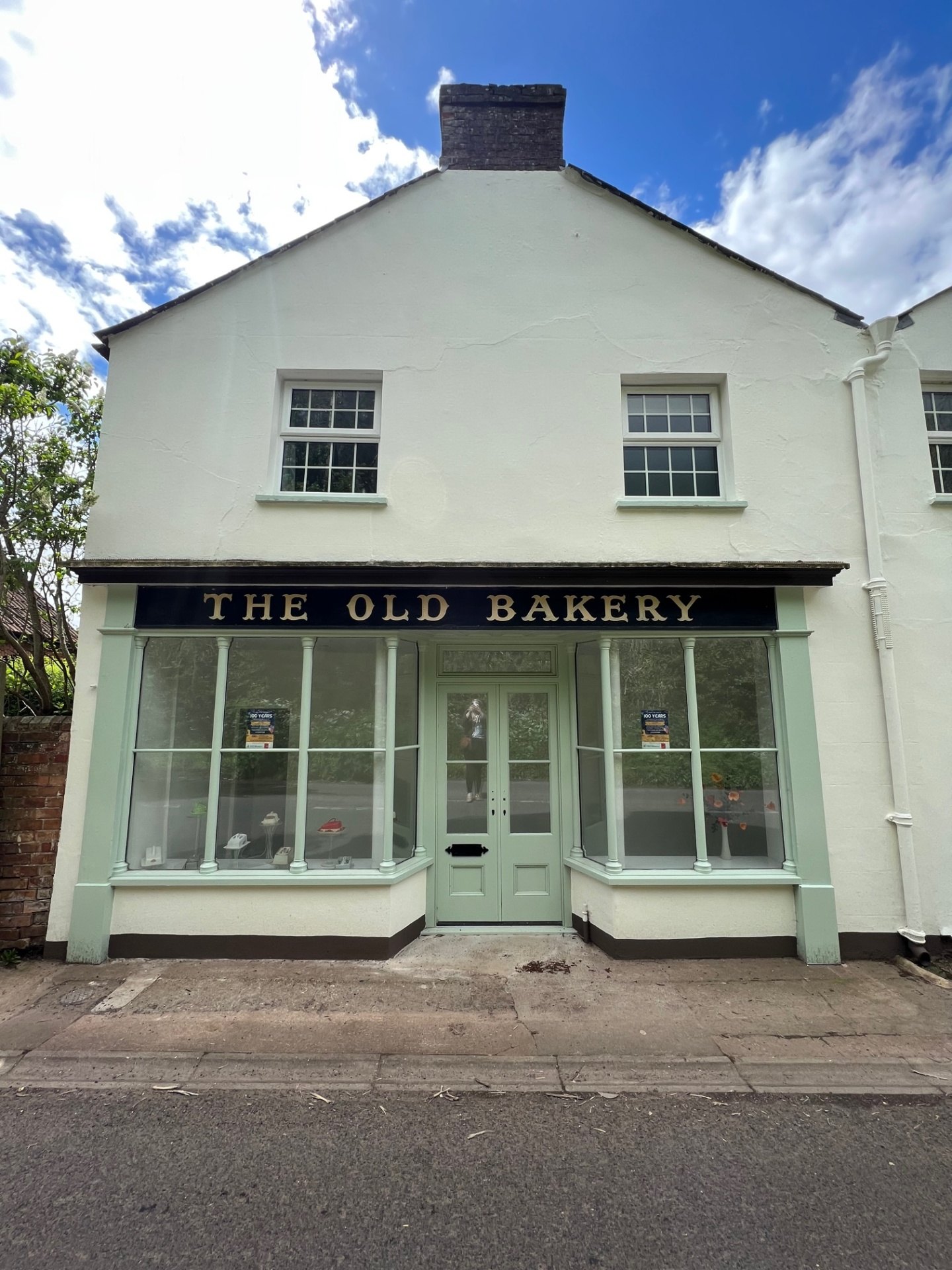 The restored Old Bakery shopfront with sage green timber windows, glazed door & navy fascia