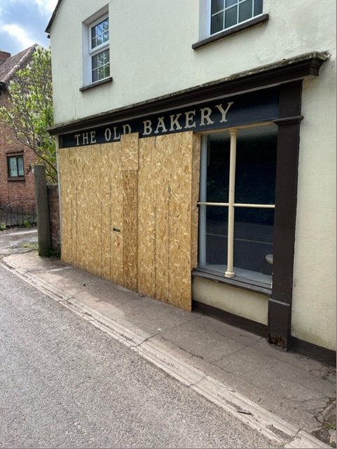 The Old Bakery shopfront boarded up with plywood after a vehicle impact